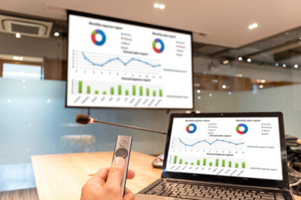 istock Businessman hand hold remote control slide with presentation on display projector screen and laptop 1448292570