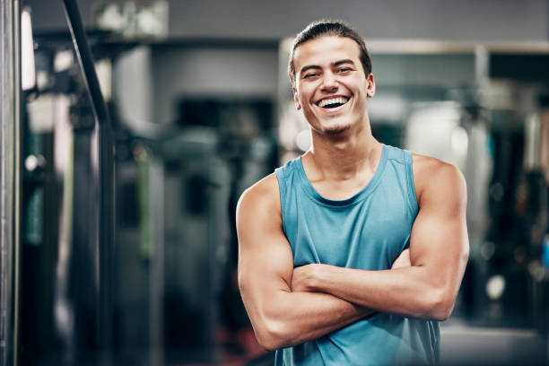 fitness, ginásio e retrato feliz do homem personal trainer pronto para o treino de coaching. treinador de treino, bem-estar e exercício confiante com os braços cruzados no health club do atleta profissional. - gym machine smiling coach - fotografias e filmes do acervo