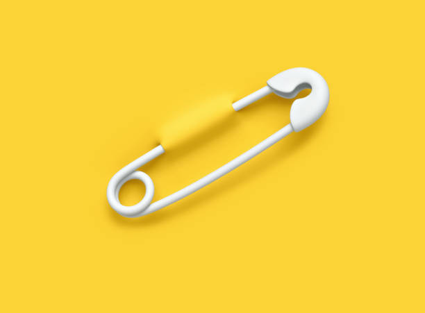 istock White safety pin pierced through yellow background. Clipping path included 1448293178