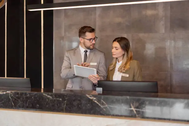Hotel receptionists using digital tablet while working at counter