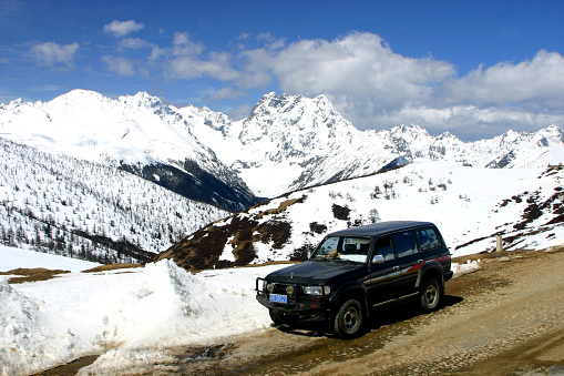 An SUV at an altitude of 4,300 m on mountain  pass. Baima (or Baimang) Snow Mountain, located in the northwest of Yunnan Province, near Tibet. the main peak is 5640 m asl. Photo in 03/10/2006, Deqin County, Yunnan