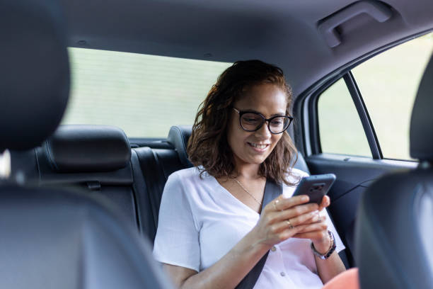 istock Woman using cell phone in back seat of car 1448303107