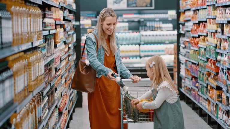 Woman and child in family grocery store with shopping cart for cooking ingredients, healthy food product or wellness goods. Smile, happy or supermarket mother and child walking in retail sales aisle