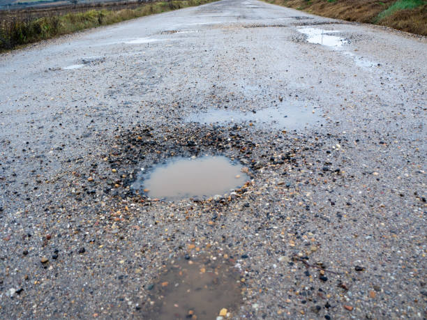 istock Pothole on a paved road on a rainy winter day. Concept of risk and traffic problems 1448310175