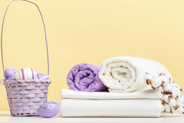istock Folded white bed linen, rolls of towels basket with easter eggs on the table 1448310238