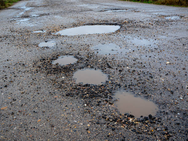 istock Pothole on a paved road on a rainy winter day. Concept of risk and traffic problems 1448310676