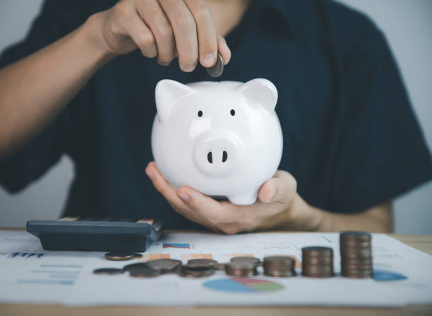 istock Man putting coins in piggy bank, saving money and stacking 1448313366