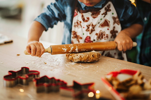 Child making Christmas gingerbread cookies. Child playing with dough close up photo.