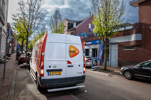 Picture of a sign with the logo of PostNL  taken on a delivery van in Vaals city center. PostNL, formerly TNT N.V., is a mail, parcel and e-commerce corporation with operations in the Netherlands, Germany, Italy, Belgium, and the United Kingdom. It provides universal delivery in the Netherlands, and is publicly listed at Euronext Amsterdam.