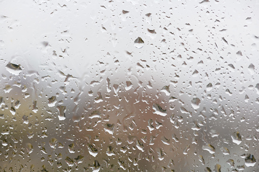 View of blurred city through the home window with raindrops. Focus on the rain drops on the glass.