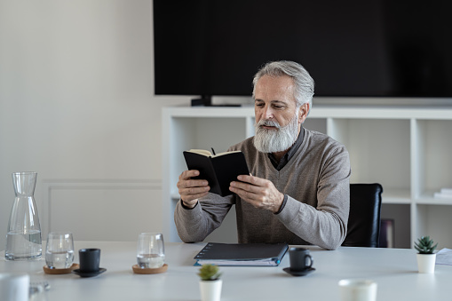 Senior business man in office with book in hand