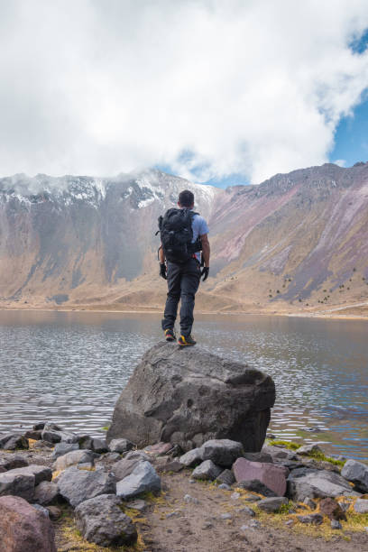 istock man with backpack looking at a lake with snowy mountains on a sunny day 1448330799