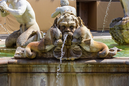 Frankfurt am Main, Germany - July 30, 2022: Water mermaids with splashing breasts at the Justitia fountain on the Römerberg in Frankfurt. Half-timbered in the background. The fountain was built in 1887 as a copy of the 1543 fountain.