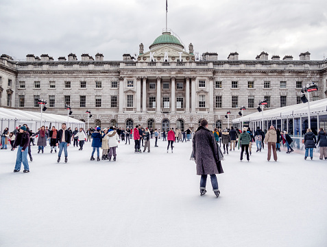 People enjoying the seasonal skating rink in the courtyard of the beautiful Somerset House in London’s Strand just before Christmas. Somerset House is a Georgian neoclassical structure surrounding a paved courtyard which is used for many events. Over the years, the 18th century buildings have served many functions but today they are used for mainly cultural purposes, including The Courtauld Institute. In the summer, the courtyard contains fountains and is known as The Edmond J. Safra Fountain Court.