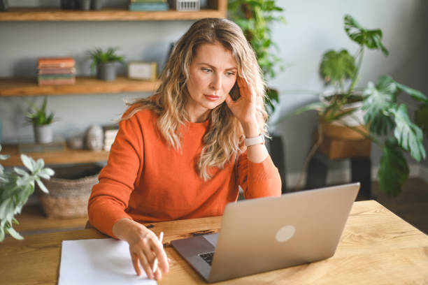 reife erwachsene frau, die zu hause arbeitet (laptop, dokument, negative emotionen) - frustration office worker women business stock-fotos und bilder