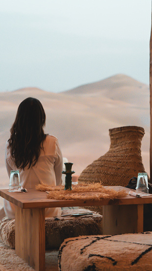 A girl seen from behind has dinner in a luxury nomad camp in the desert