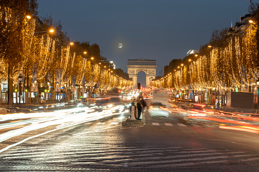 View of the Arc-De-Triomphe and Avenue des Champs Elysees with Christmas lights and full moon