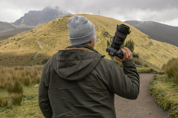 istock holding professional camera, modern work tool with landscape on the background, hobby 1448345783