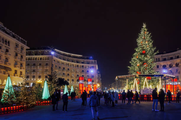 Thessaloniki, Greece - December 8 2022: decorated and illuminated Christmas tree at Aristotelous square. Night view of festive installments at the southern part of main city square, with crowd. stock photo