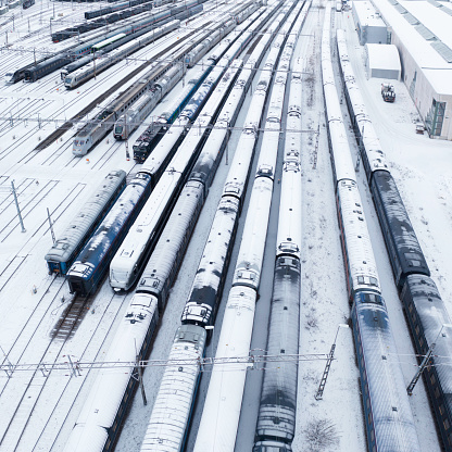 A large number of snow covered trains in a rail yard in winter.