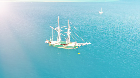 Sailing ship sails in a wonderful crystal clear sea, aerial view from drone.