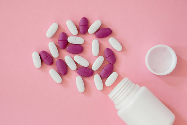istock White plastic bottle and scattered pills on pink background, top view, flatlay, close up. 1448353799