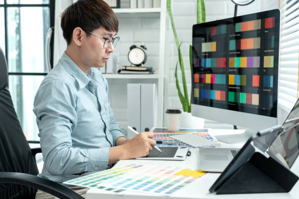 istock Male graphic designer is choosing color swatch samples on multiple screens and sketching on tablet digital to working graphic design with technology in modern office 1448355208