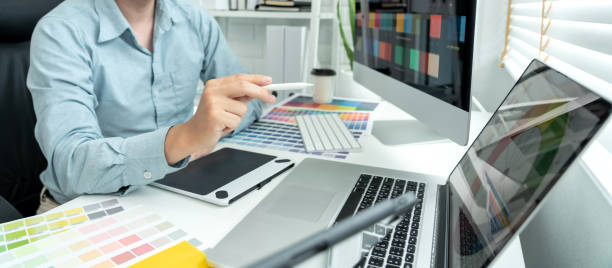 istock Male graphic designer is choosing color swatch samples on multiple screens and sketching on tablet digital to working graphic design with technology in modern office 1448355222