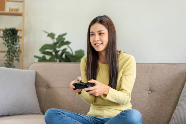 istock Young asian woman is using video game control joystick to playing games with enjoyment while sitting 1448355498