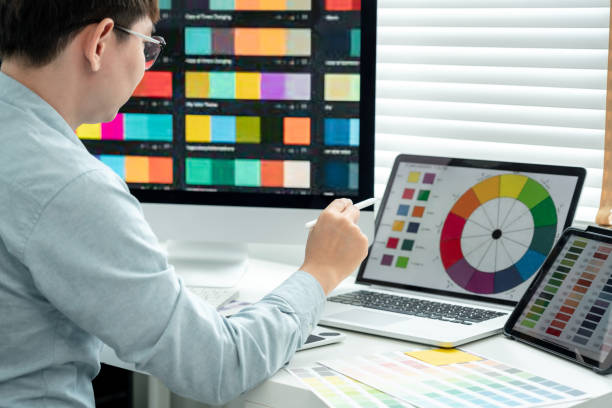 istock Male graphic designer is choosing color swatch samples on multiple screens and sketching on tablet digital to working graphic design with technology in modern office 1448355561