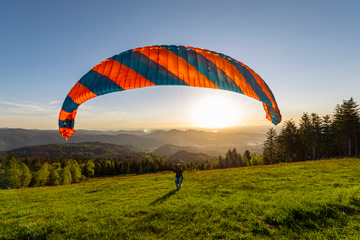 Paraglider at the take-off site at the Devil's mill in the Murg valley in the Black Forest spreads his paraglider against the afternoon sun, Germany