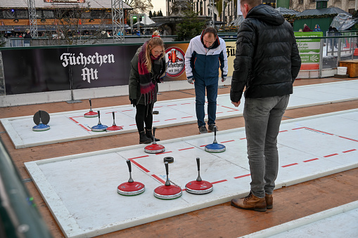 Duesseldorf, Germany, December 9, 2022 - Unknown athletes play curling on the Corneliusplatz in Duesseldorf. The plastic rink / ice skating surface is set up in the months of November and December as part of the \