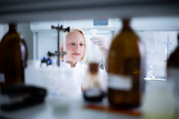 Young female scientist examining liquid while working on scientific research in laboratory.