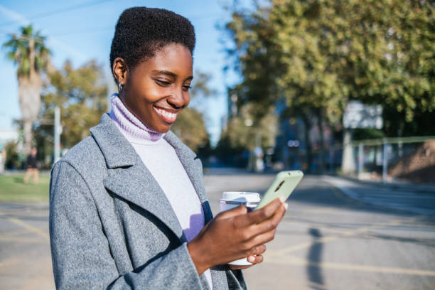 istock Happy black woman using smartphone on street 1448358259