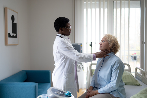 Black female doctor examining patient's throat during an appointment in hospital.