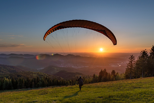 Paraglider at the take-off into the sunset at the Devil's mill launch site in the Murg valley in the Black Forest mountains, Germany