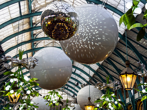 Christmas baubles, lanterns and oversized mistletoe hanging from the glazed domed ceiling in London’s Covent Garden Market.