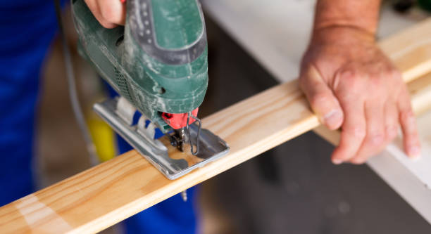 istock Cropped view of man using a jigsaw machine on wooden plank at home 1448362886