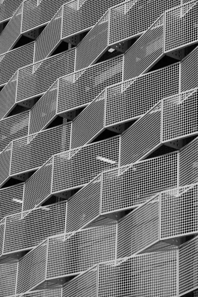 Modern steel cladding with angular geometric patterns and square holes in a shiny metal