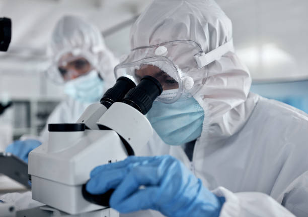 istock Hazmat suit scientist, microscope and laboratory research analysis, dna test and vaccine development of medical bacteria risk. Science expert team, chemistry workers and healthcare analytics with ppe 1448367157