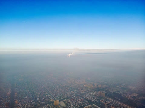 Aerial view of polluted city from burning fossil fuel covered with smog during winter