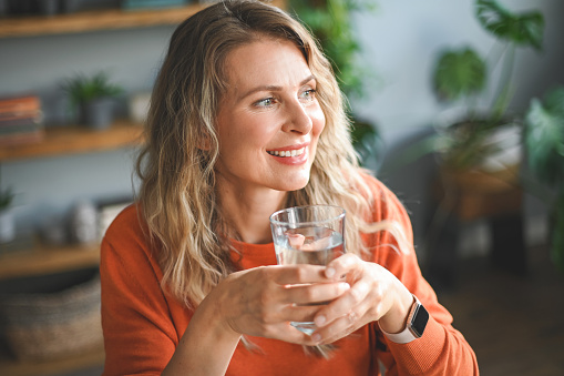 mature adult woman drinking water from a glass