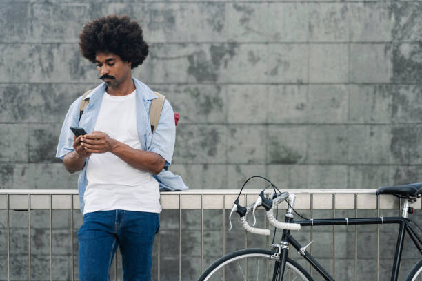 istock Young African American Man commuter to work with bicycle using smartphone cell phone in the city 1448368418