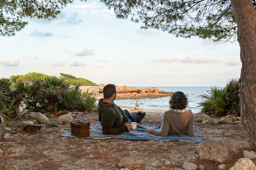 Heteroxesual couple enjoying a coffee at a mediterranean beach on an autumnal evening.
