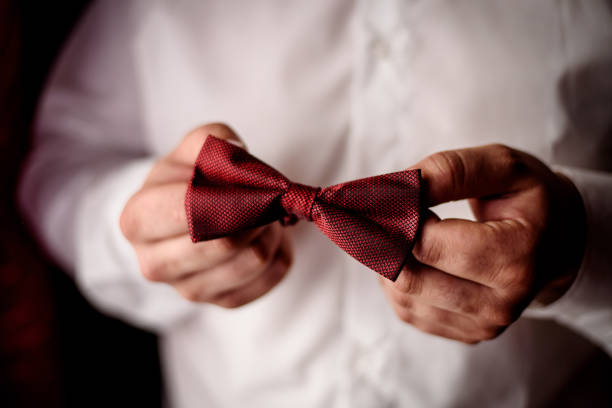 The groom holds a bow tie in his hands. High quality photo