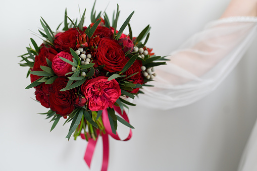 A bride displays her bouquet of red roses encircled by the white rose bouquets of her bridesmaids.
