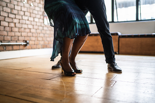 Low-section of senior couple practicing steps in the dance hall