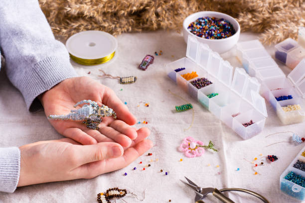 istock Bird woven from beads in children's hands among boxes with beads 1448374673
