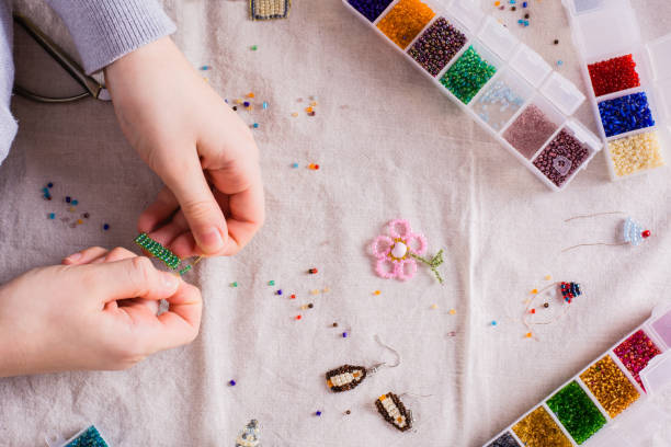 istock Children's hands weave a beaded toy on a table among boxes with beads. Top view 1448374711
