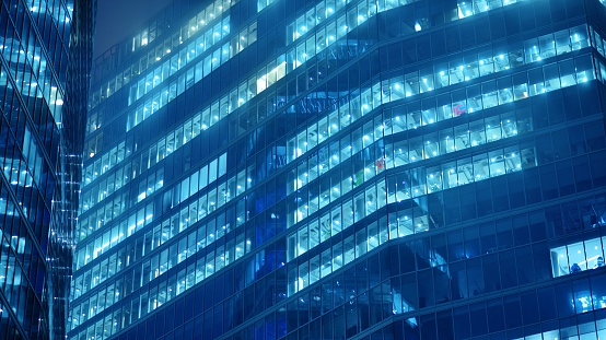 Glass architecture ,corporate building at night - business concept. Blue graphic filter.